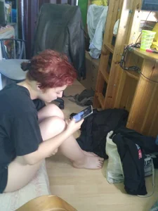 Cute Ginger Barefoot Teen in a T-Shirt And Panties Sitting on the Floor With Her Phone