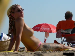 Topless tattooed lady at the beach with a nice ass in pink thong bikini