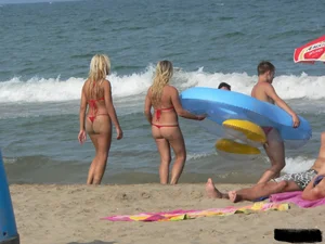 Sexy mom and daughter in red thongs at the beach