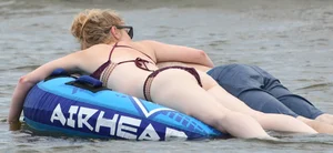 Chunky blonde enjoying some drinks in the water in her purple bikini