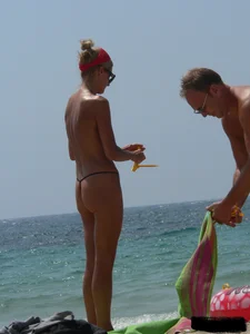 Topless skinny blonde lady in a g-string bikini at the beach