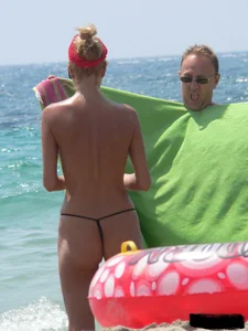 Topless skinny blonde lady in a g-string bikini at the beach