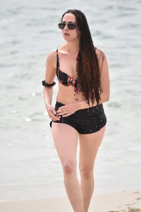 Brunette girl in black shorts and bikini top on the beach
