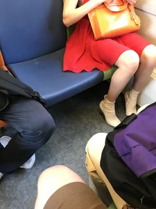 Sexy legs of a candid girl wearing a short red dress, sitting in a public train