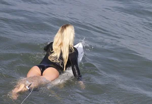 Blonde surfer lying on her board