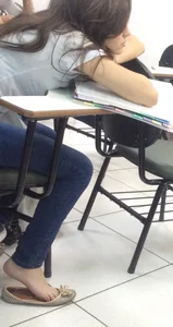College teen in tight jeans and flats dangle in class