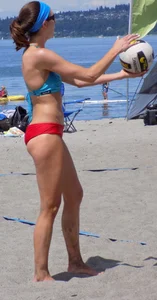 Skinny mature lady in red bikini bottom on the beach playing volleyball