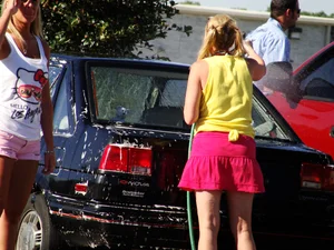 Group of cute girls at a car wash in bikinis and shorts