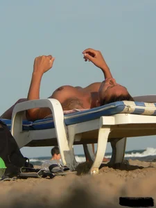 Topless tattooed lady on the beach with fake big tits