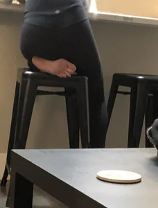 Barefoot girl sitting on a bar stool