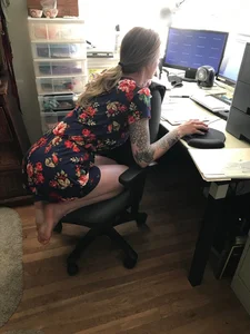 Girl in a Dress Standing on Knees on the Office Chair Shoeless