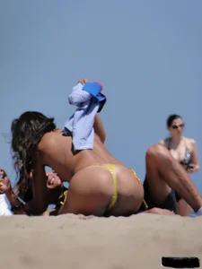 Topless lady on the beach in a gold thong with a nice ass