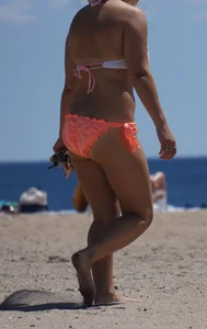 Thick blonde girl in an orange bikini on the beach
