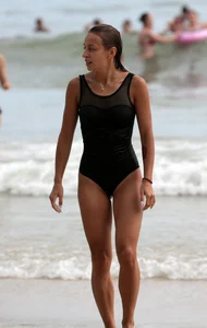 Skinny sexy lady on the beach in a black swimsuit