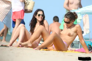 2 topless girls at the beach in thongs