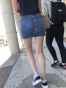 Cute Girl in a Short Denim Skirt Walking on a Street And Waiting on a Crosswalk Gallery