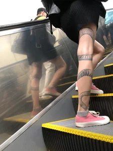 Girl in a Skirt With a Snake Tattoo on Her Leg Standing With Spread Legs on an Escalator Creepshots Series