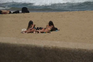 Two babes laying on the beach in bikinis with nice asses