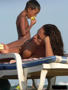 Topless tattooed lady on the beach with fake big tits