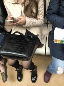 Cute girl with skinny legs in black pantyhose sitting in a subway train