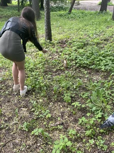 Skinny girl in a short dress bending over to feed a squirrel