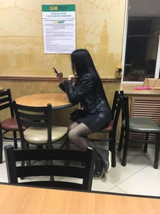 Girl in a Skirt and Black Pantyhose Sitting in the Cafe Candid