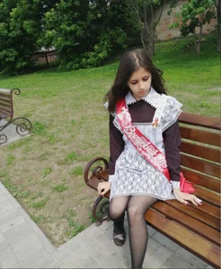 Cute girl wearing a dress and black pantyhose sitting on a park bench, nice legs