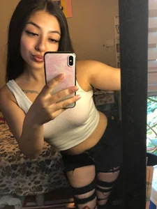 Hot girl in a top and torn jeans selfie in the mirror