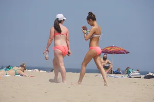 Two sexy girls in peach and pink bikinis on the beach