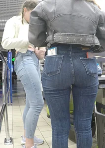 Two hot milfs in tight blue jeans standing at the cash register at the supermarket, awesome big butts