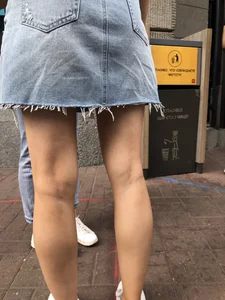 Hot slim legs closeups, street girl wearing a denim fringed skirt