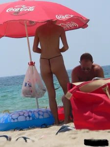 Topless skinny blonde lady in a g-string bikini at the beach