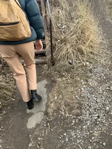 Candid girl wearing pants and a backpack walking down a suburban road