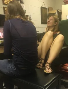 Candid Girl in Mini Shorts And Sandals Sitting With Her Feet on Chair Laughing