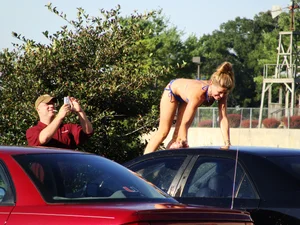Group of cute girls at a car wash in bikinis and shorts