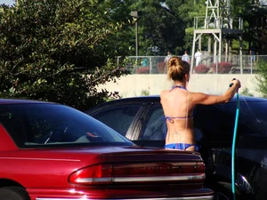 Group of cute girls at a car wash in bikinis and shorts