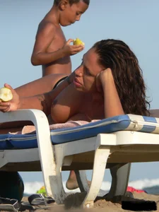 Topless tattooed lady on the beach with fake big tits
