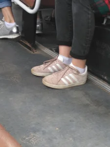 Young Candid Girl's Feet in Tight Jeans, Short White Socks And Sneakers in a Public Bus Closeup Creepshot