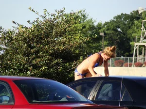 Group of cute girls at a car wash in bikinis and shorts