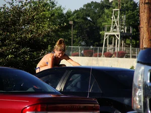 Group of cute girls at a car wash in bikinis and shorts