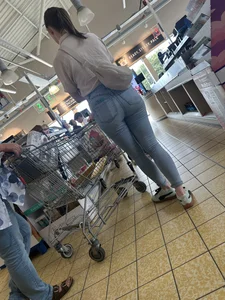Tight cheek hugging jeans on brunette in line at shop