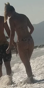 Smooth bodied and sexy blonde at the beach in a thong bikini