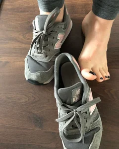 Teen college girl taking off sneakers with no socks on, closeup of her feet