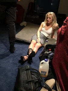 Hot Blonde Girl in High-Heeled Shoes and a Skirt Sitting on the Floor at the Party Creepshots