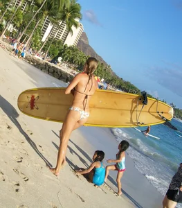 Skinny blonde surfer on the beach in little bikini