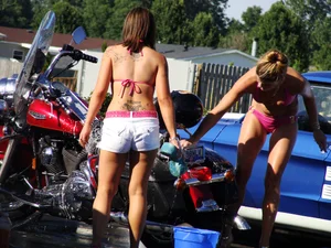 Group of cute girls at a car wash in bikinis and shorts
