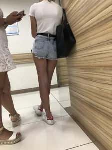 Hot Tanned Girl in Blue Denim Shorts Standing with Crossed Legs