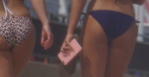 Two sexy friends, one blonde and one brunette, on the beach in bikinis