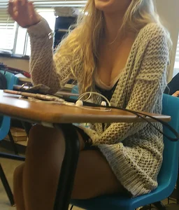 Cute College Blonde in a Sweater Sitting at a Desk with Crossed Legs