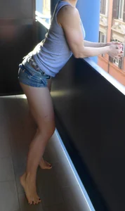 Girl in Mini Shorts Standing on Balcony Barefoot